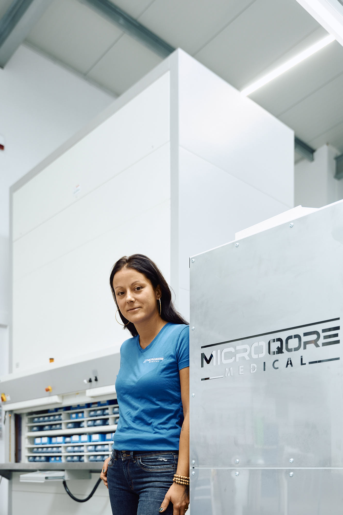 MICROQORE Mitarbeiterin am Ersatzteillager neben dem Firmenlogo